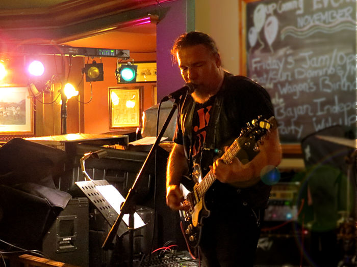 Geoff Paice playing lead guitar while moodily
                  lit