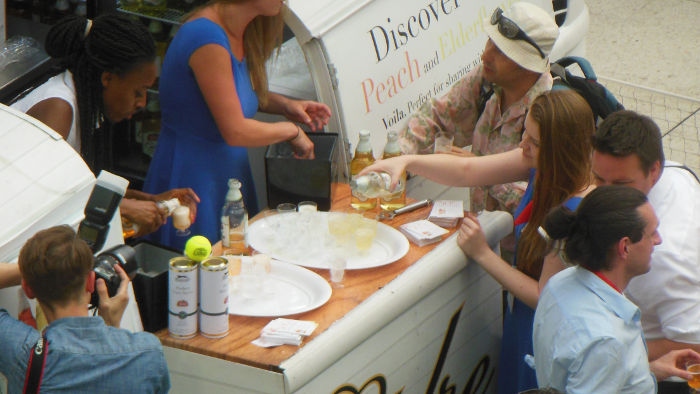 Man with a big lens takes a picture of
                          someone getting a free sample of cider