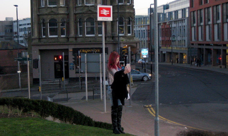 Sue by a Hastings
                      station sign